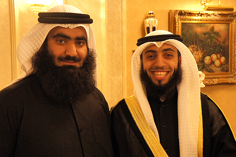 two people smiling for the camera, one is dressed in a robe and the other has a beard