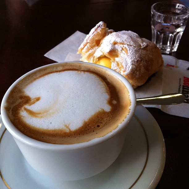 a white mug with coffee in it is sitting on a plate