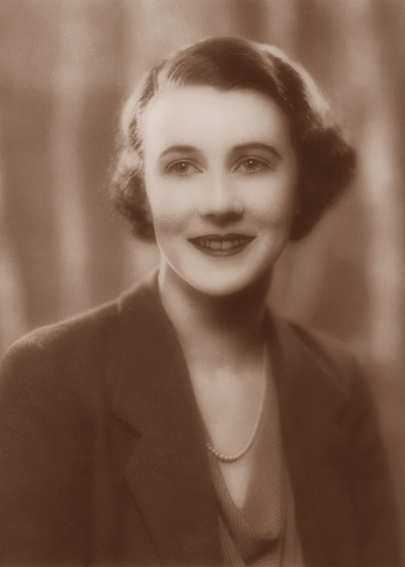 a woman posing for a pograph wearing a suit and a necklace