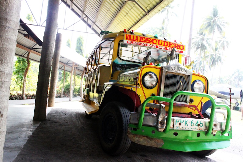 a bright colored bus is parked under a large metal shelter