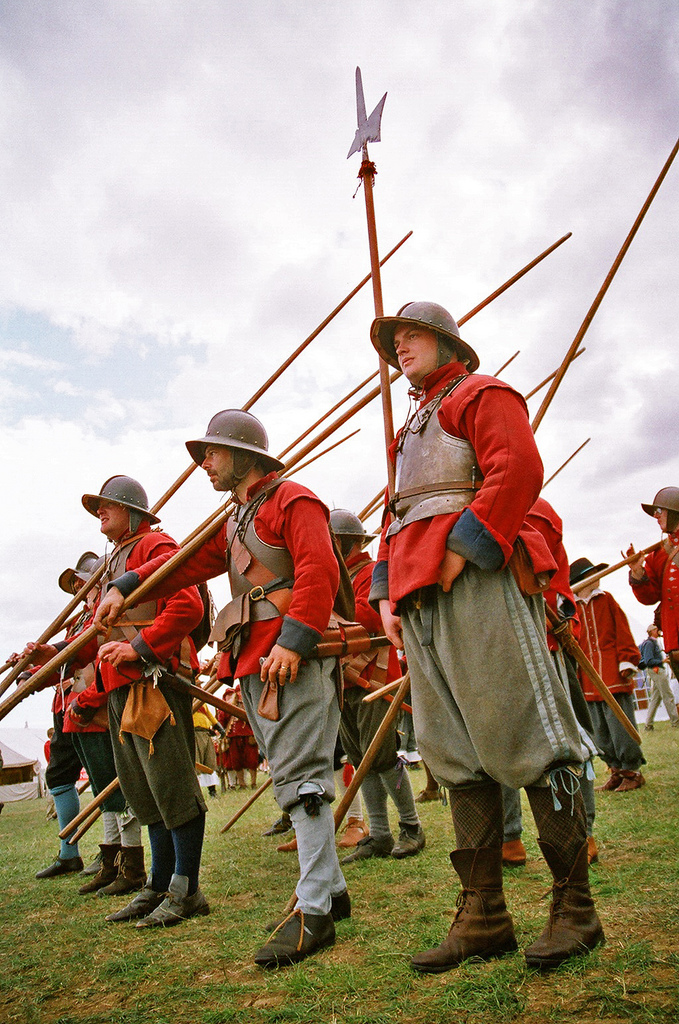men in battle costume holding flags on grass field