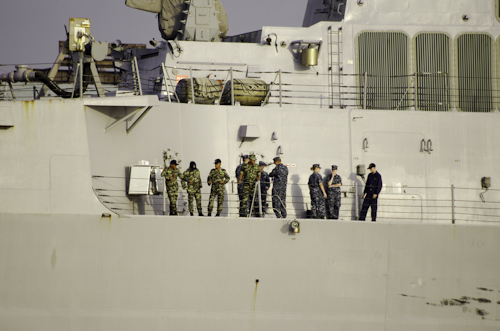 men in military uniforms are on the top deck of a ship