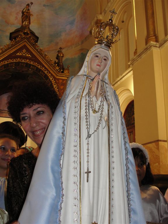 two women smile and stand near a sculpture of the virgin mary