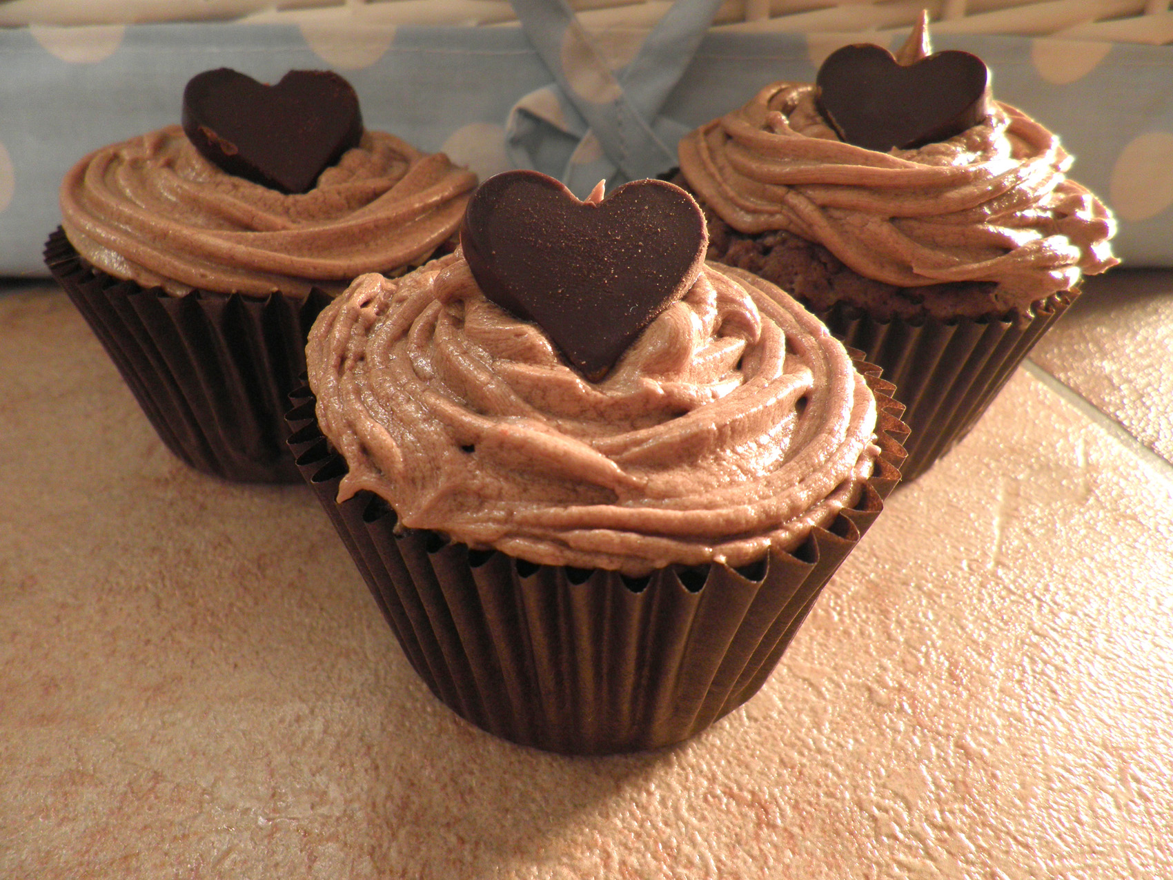 three cupcakes in the shape of hearts, with a bow on top