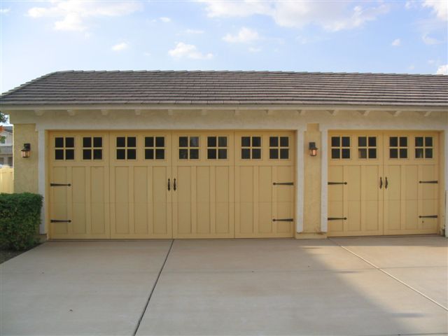 a yellow garage with four windows and a tile roof
