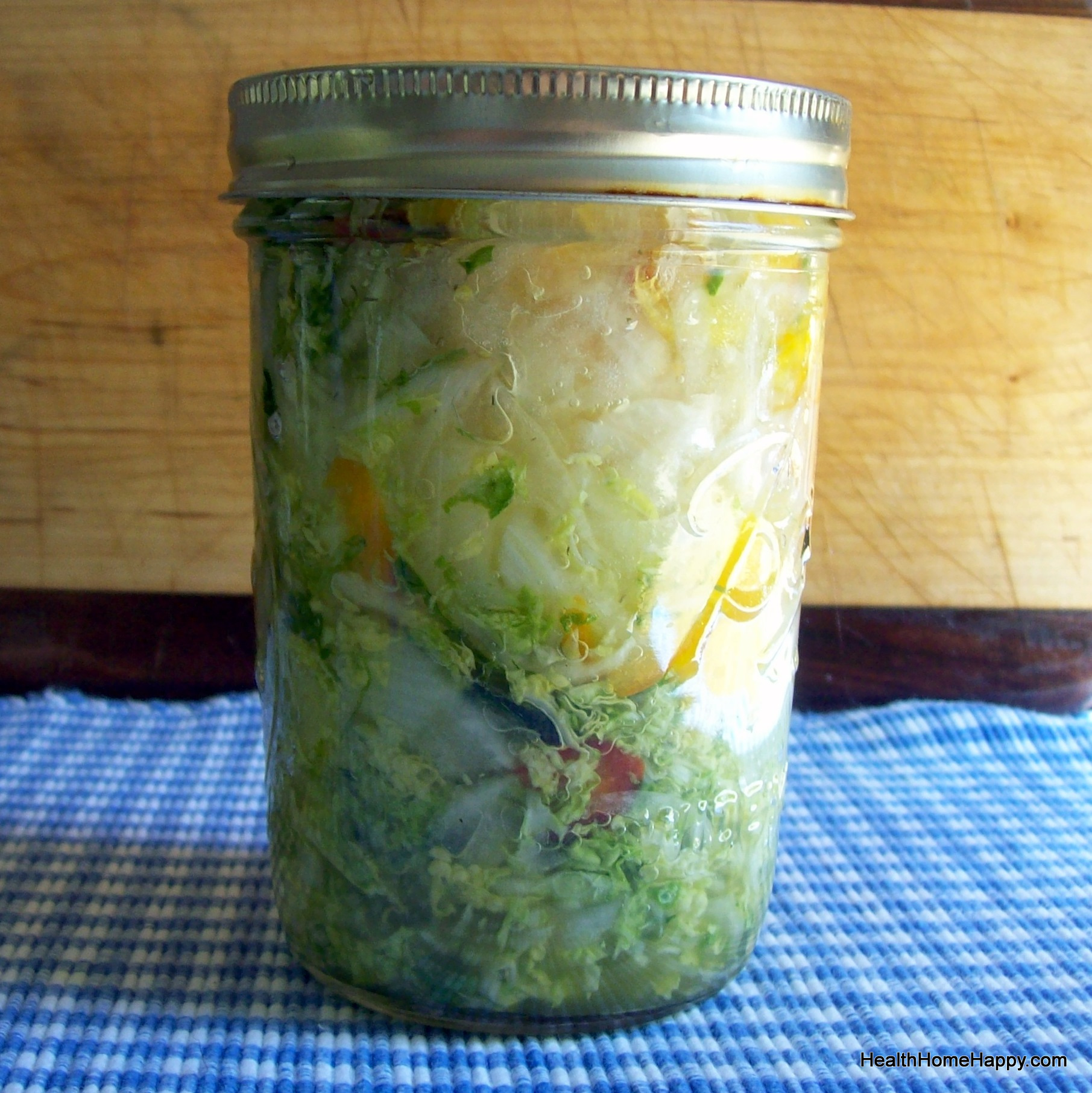 a glass mason with cabbage and other vegetables inside