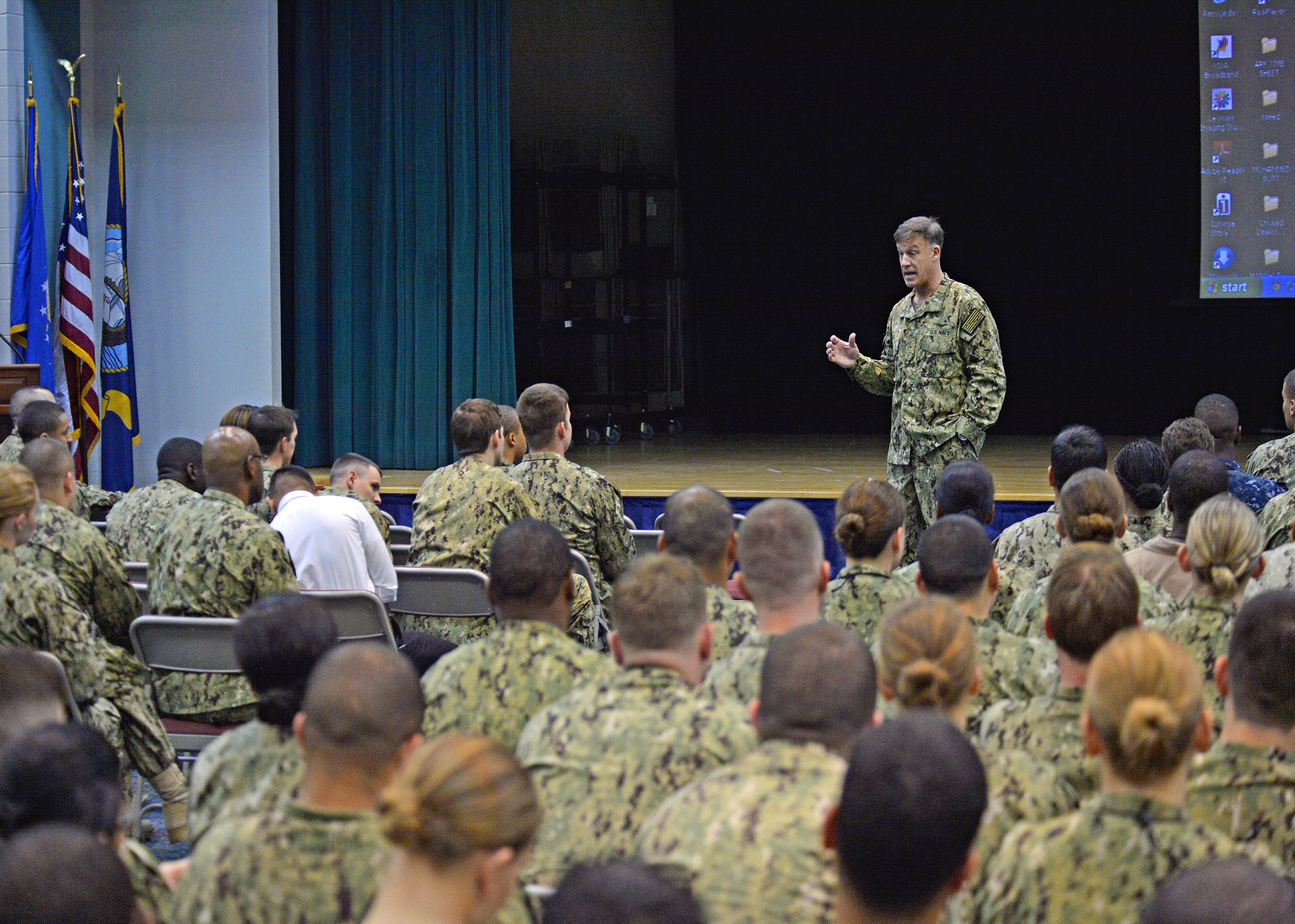 the man is in uniform speaking to a large group