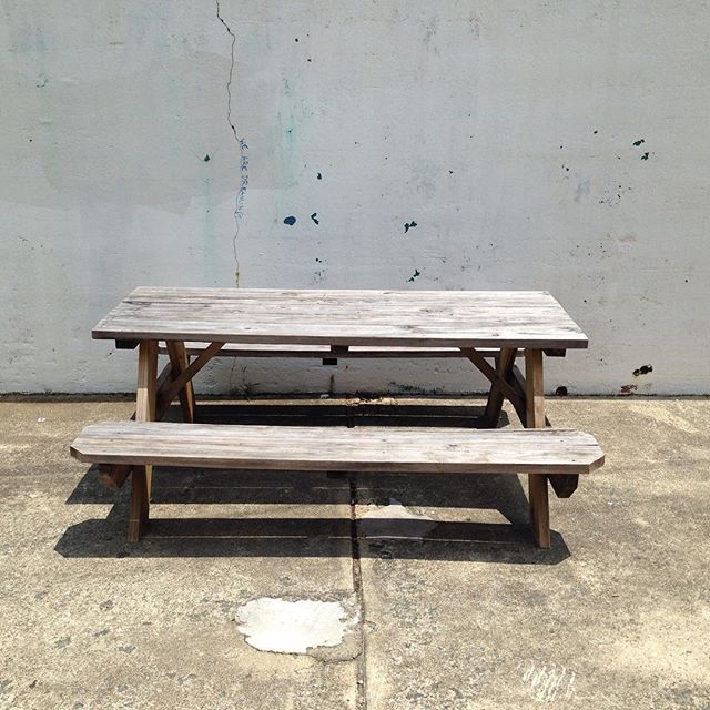 an old picnic table sits beside an old wall