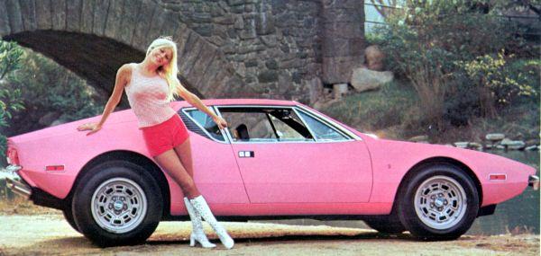 a woman standing by the rear end of a pink sports car