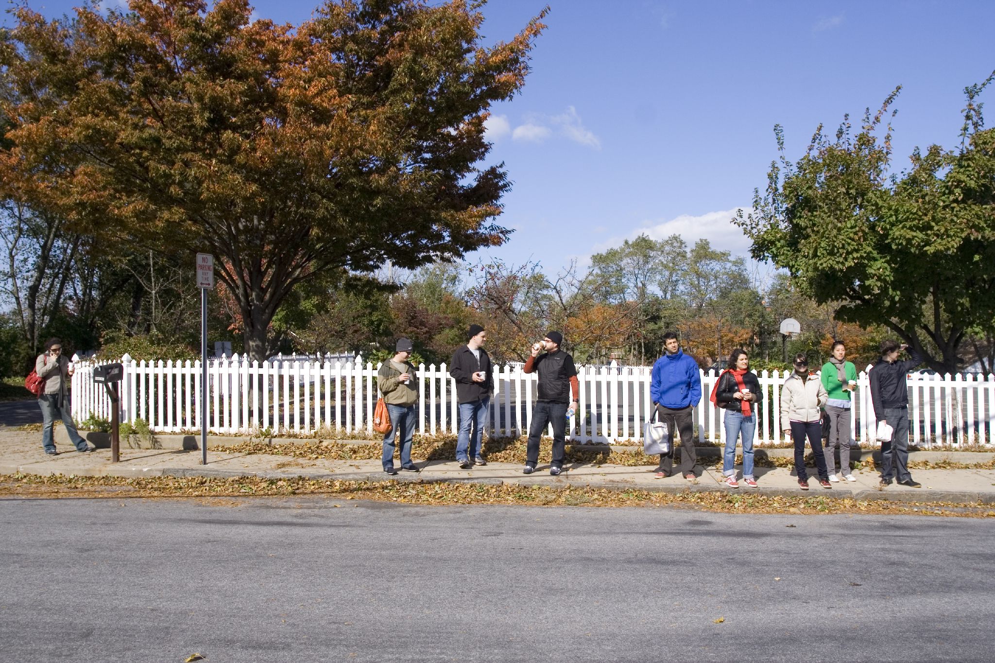 group of people standing on the sidewalk by the road