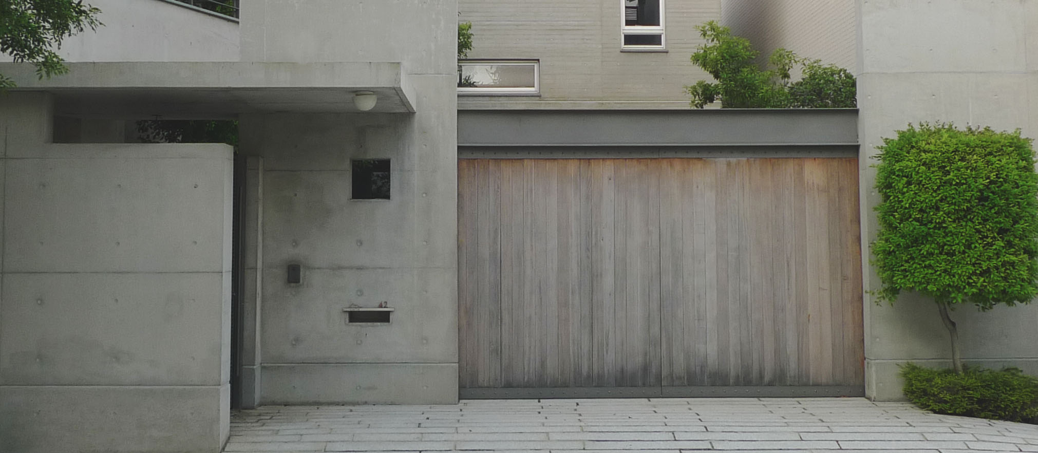 a brown door stands against a tall grey building