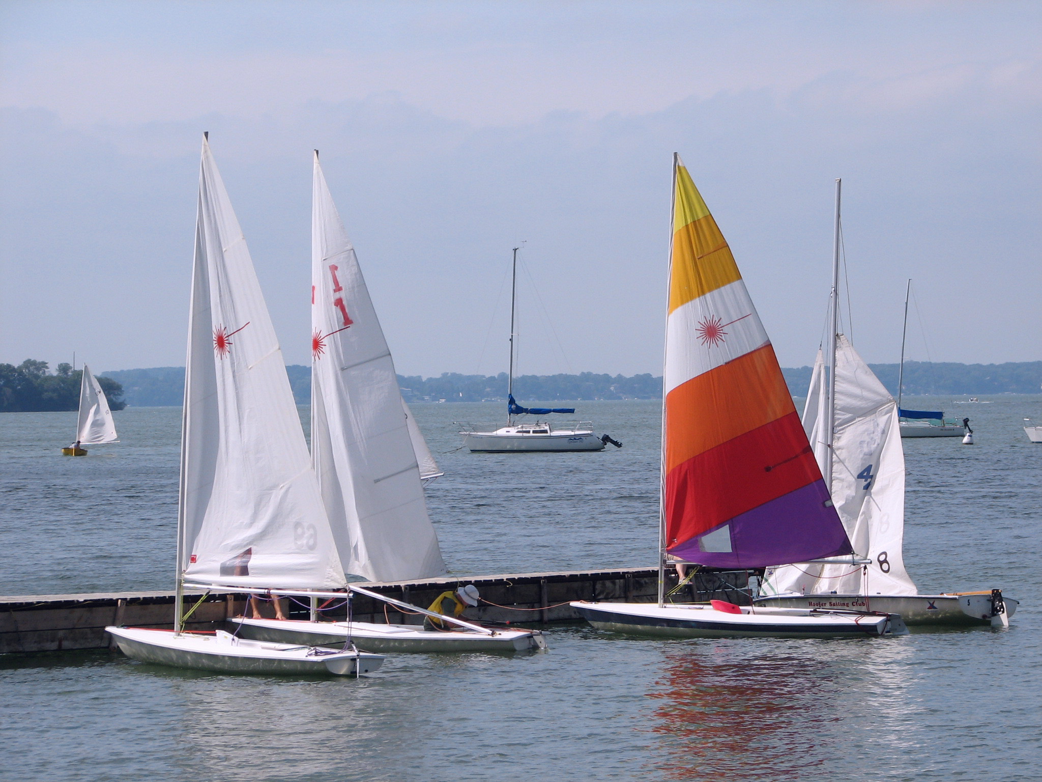 small sailboats lined up on a pier in a harbor