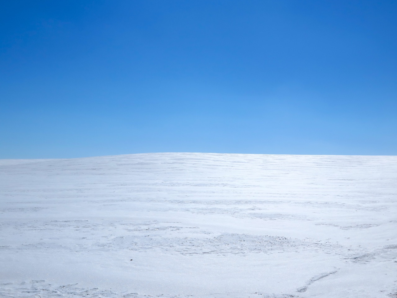 a lone man is skiing across a large snow covered field