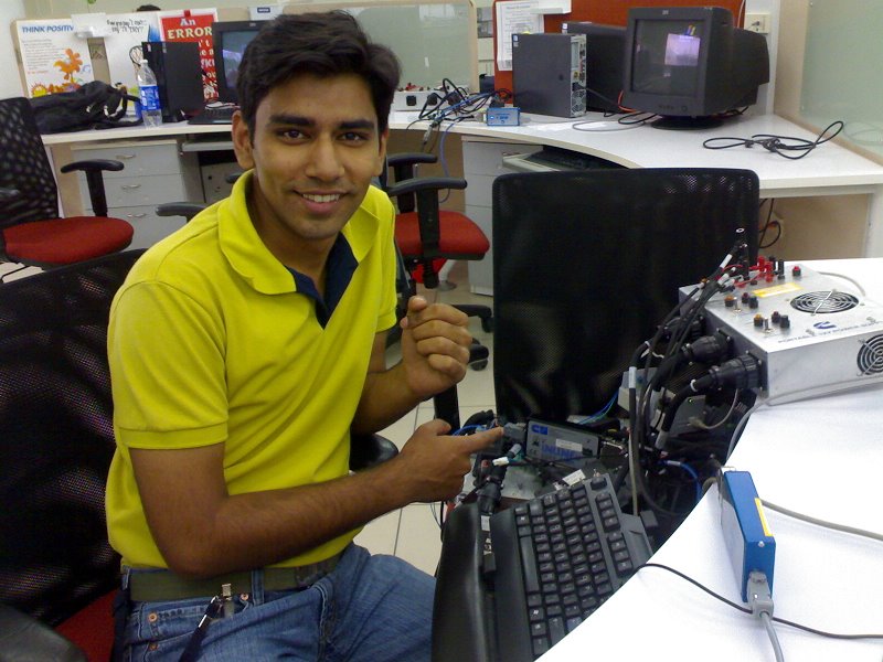 a smiling guy sits next to a large computer