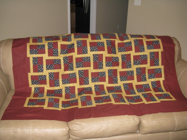 a quilted blanket dd on the back of a couch