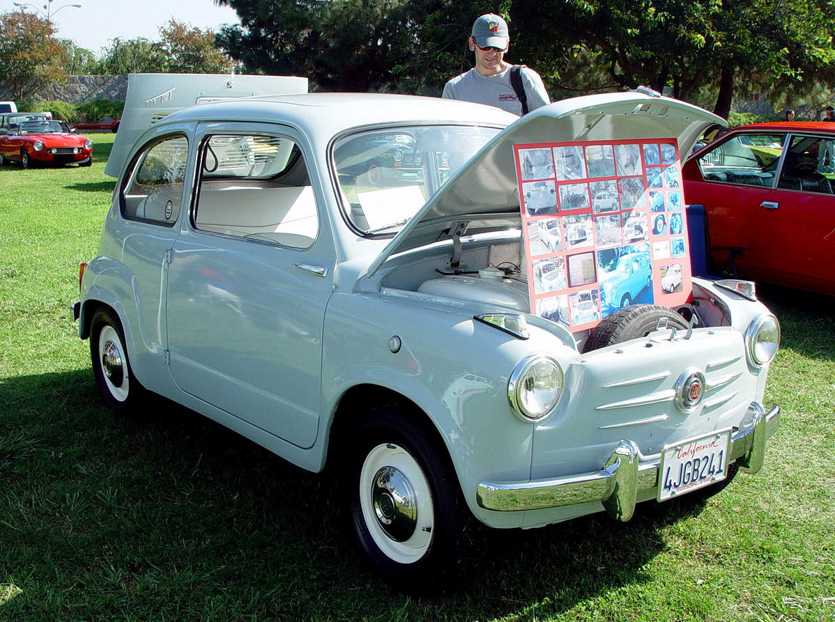 a man standing next to an old white car