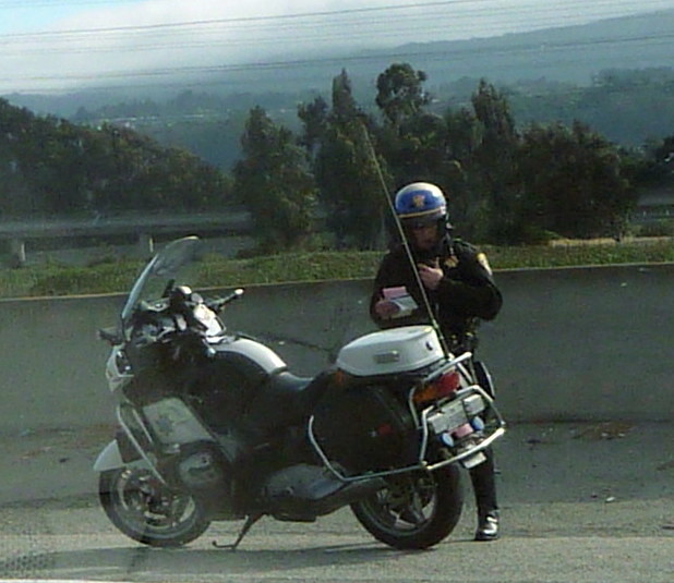 a motorcyclist leans against his parked motorcycle