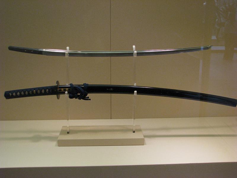 a sword is displayed behind glass with a white stand