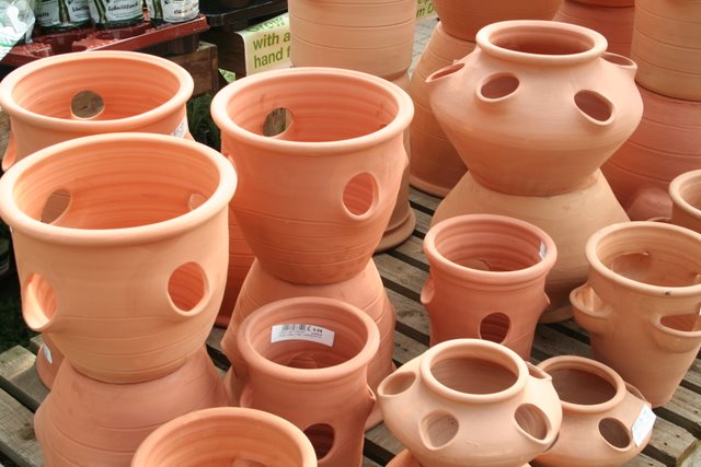 a display of orange clay pots on a wooden stand