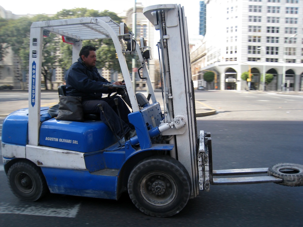a man driving a forklift on a city street