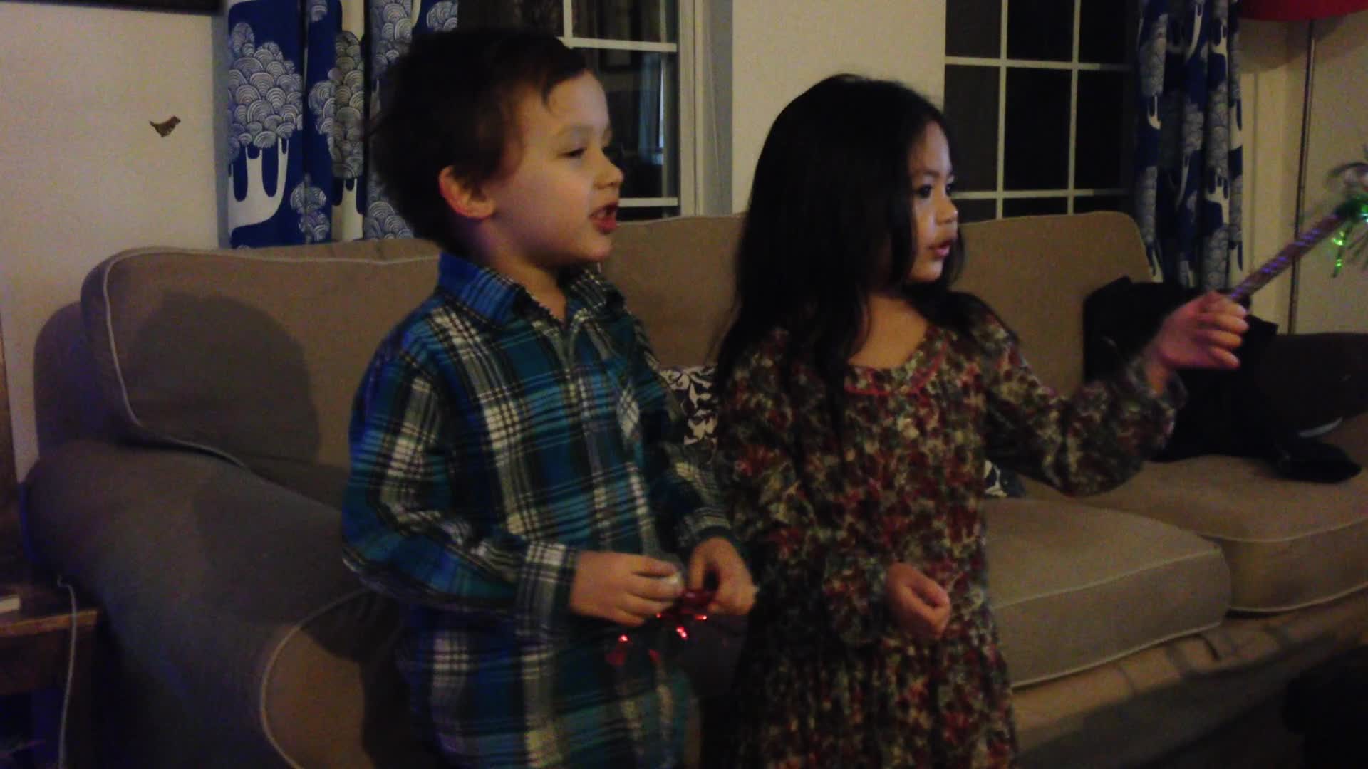 two young children standing in front of a couch holding nintendo wii controllers