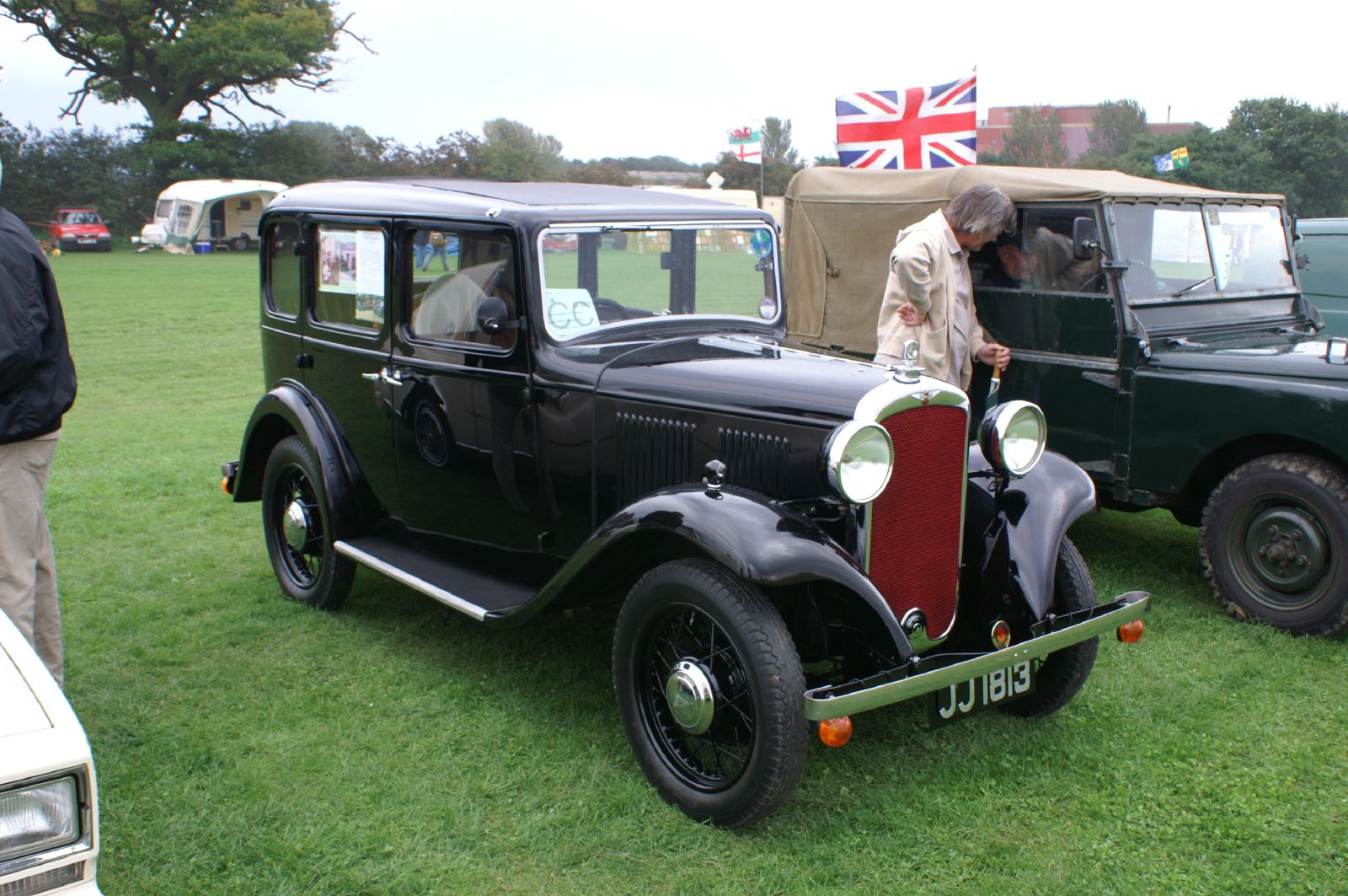a man standing next to an old time jeep on display