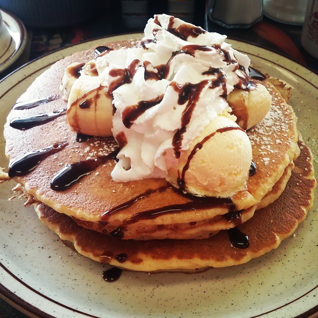 a stack of pancakes topped with whip cream and chocolate syrup