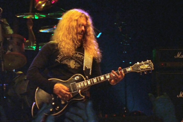 an electric guitar player with long hair is performing