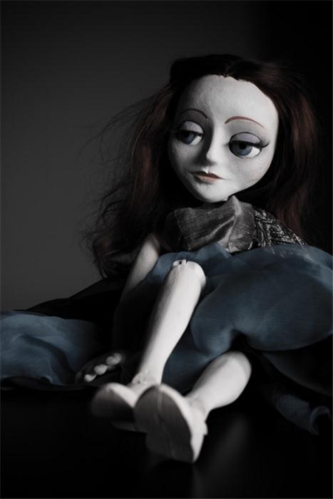a doll laying down on a bed with blue sheets