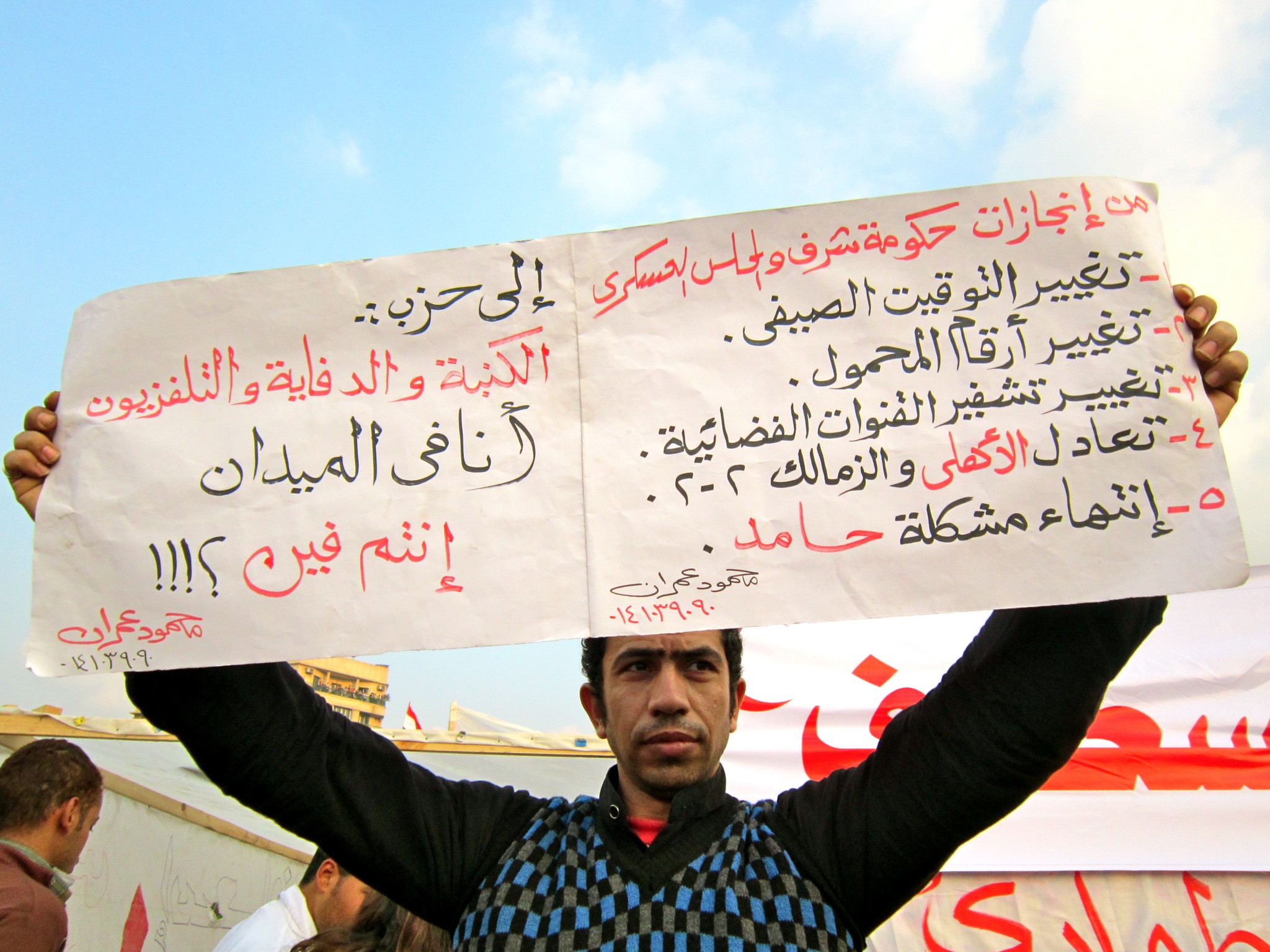 a man holding two signs with two other men standing behind them