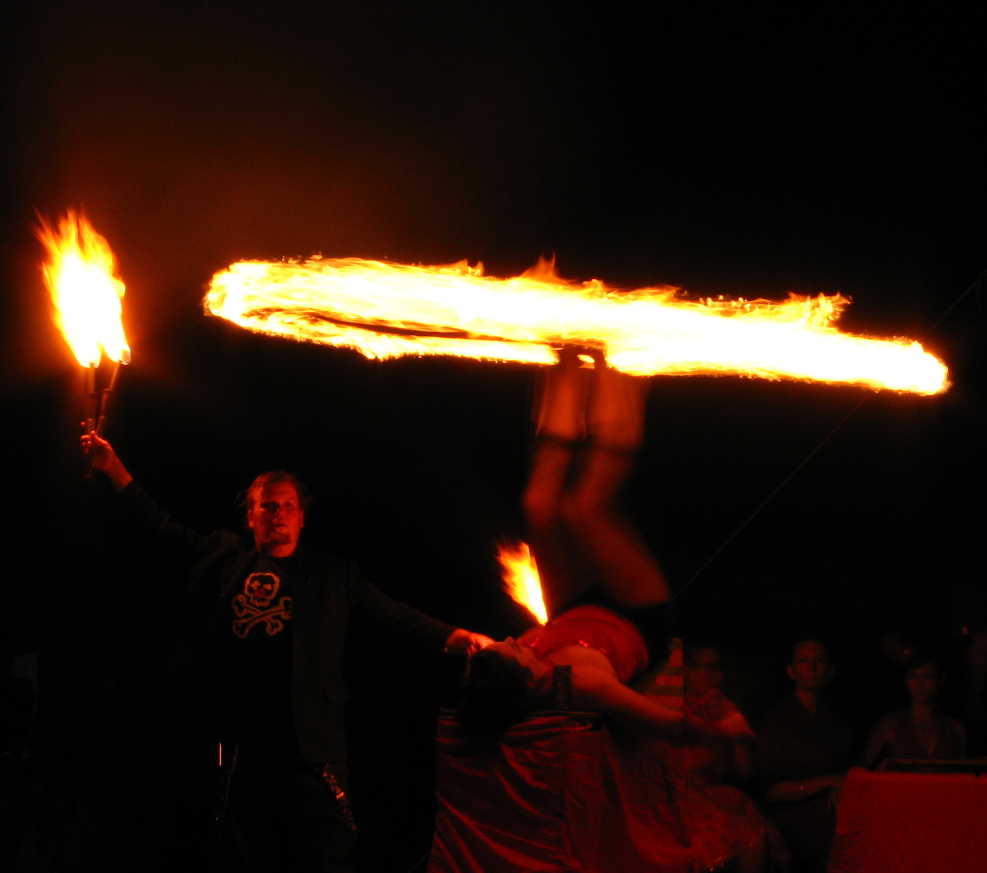 man holding torches in the dark with fire swirling