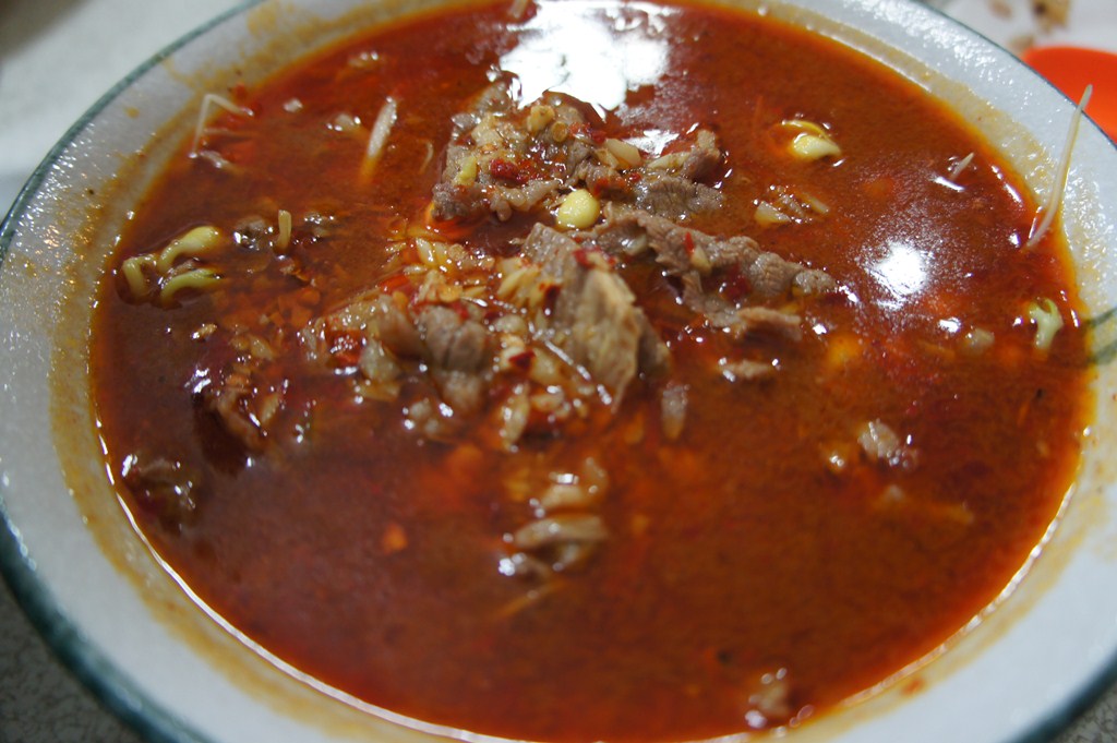 a soup bowl is full of meat stew and a side of bread