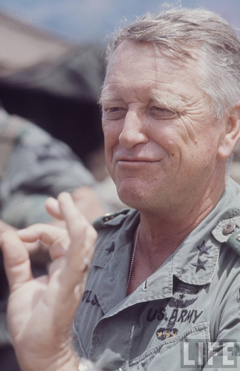 a smiling man in an army uniform holding a cigarette