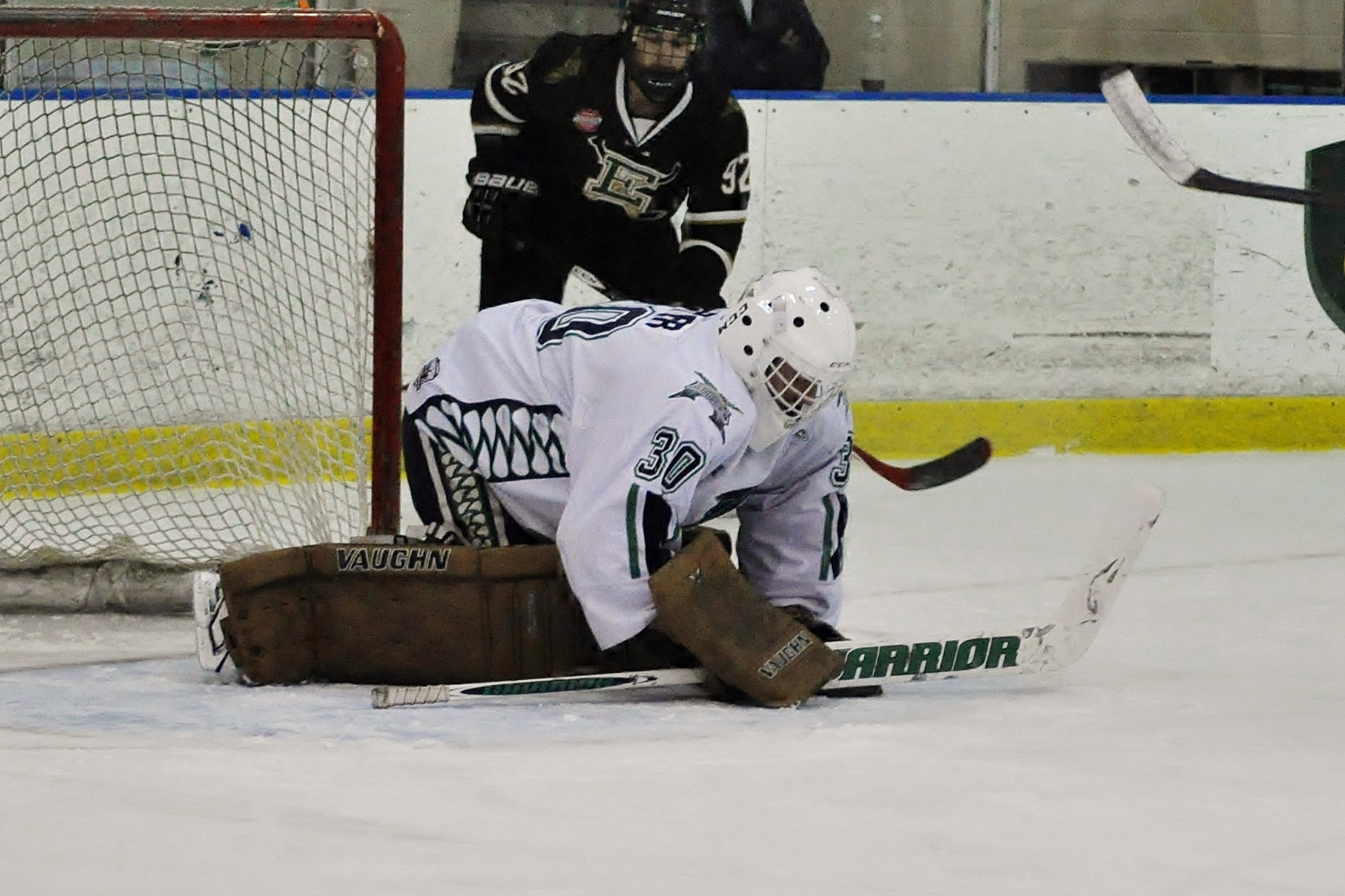 a young hockey player falls over after hitting the goal