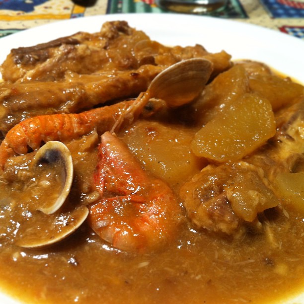 a dinner plate with meat and seafood on a colorful tablecloth