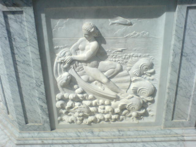 a marble plaque with a girl and seashells carved into it