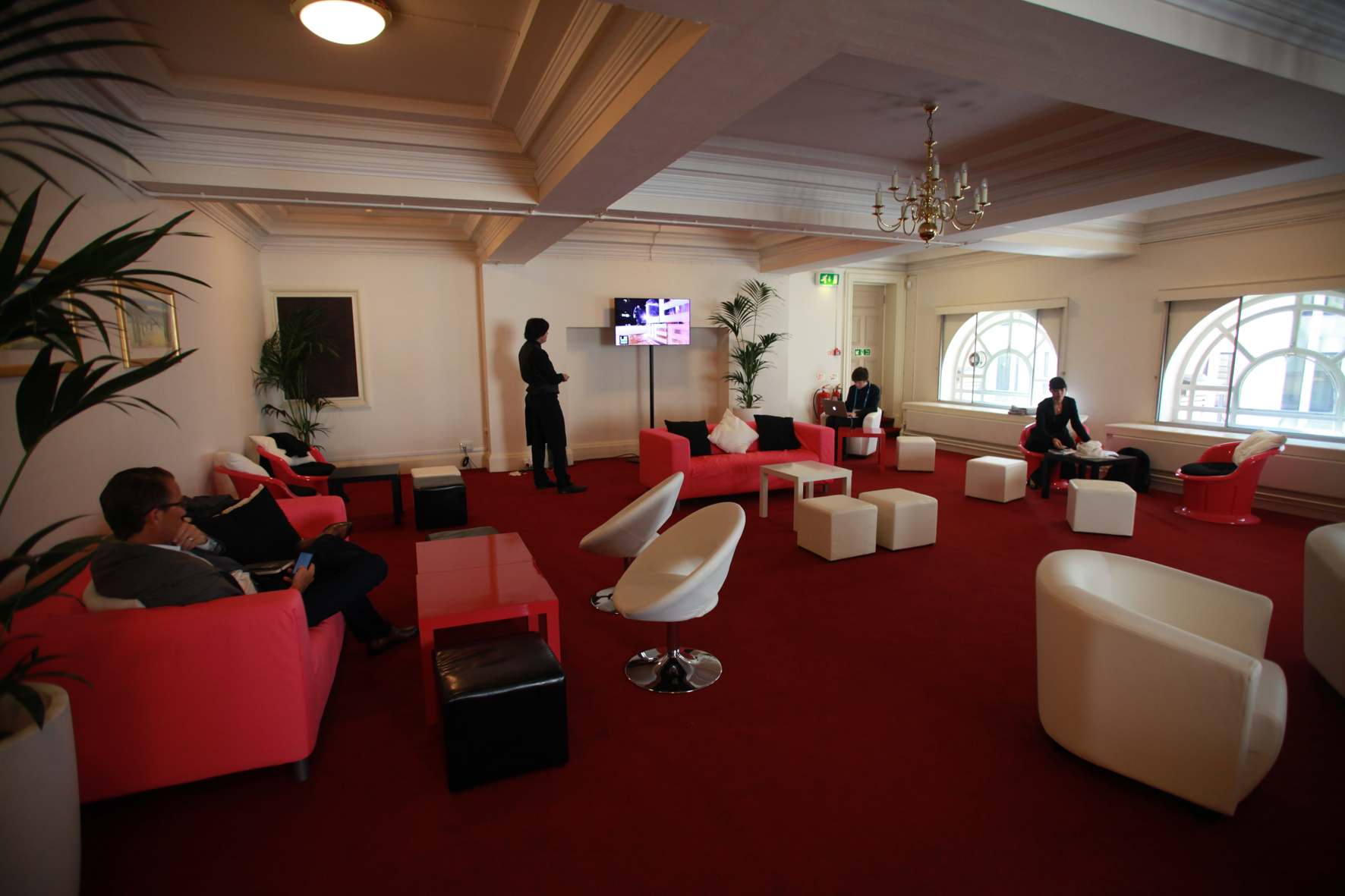 men are sitting on red chairs in an ornate room