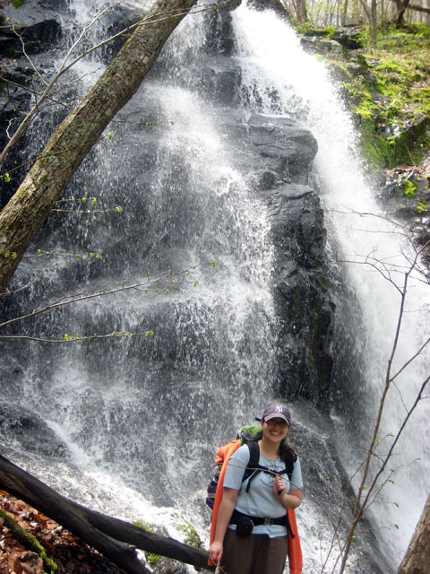 a young woman stands at the top of a waterfall