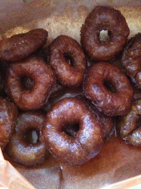 brown donuts piled into a bowl on top of a table