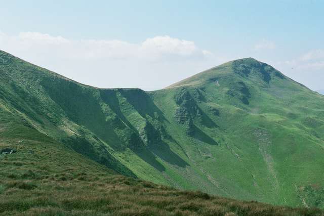 large green hills with grass and bushes on top