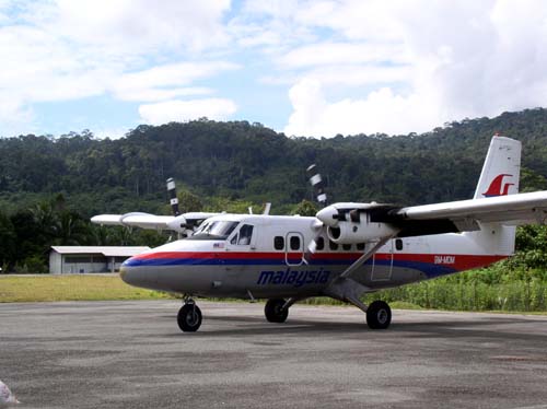 a large airplane on a small runway with a person standing next to it