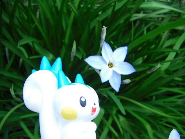 a toy animal with horns standing near two flowers