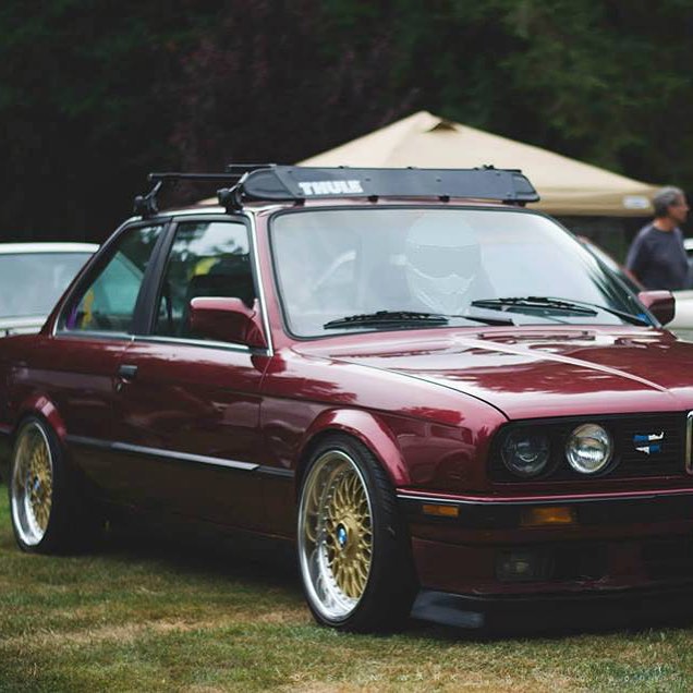 a maroon bmw car with a pair of gold rims on its wheels