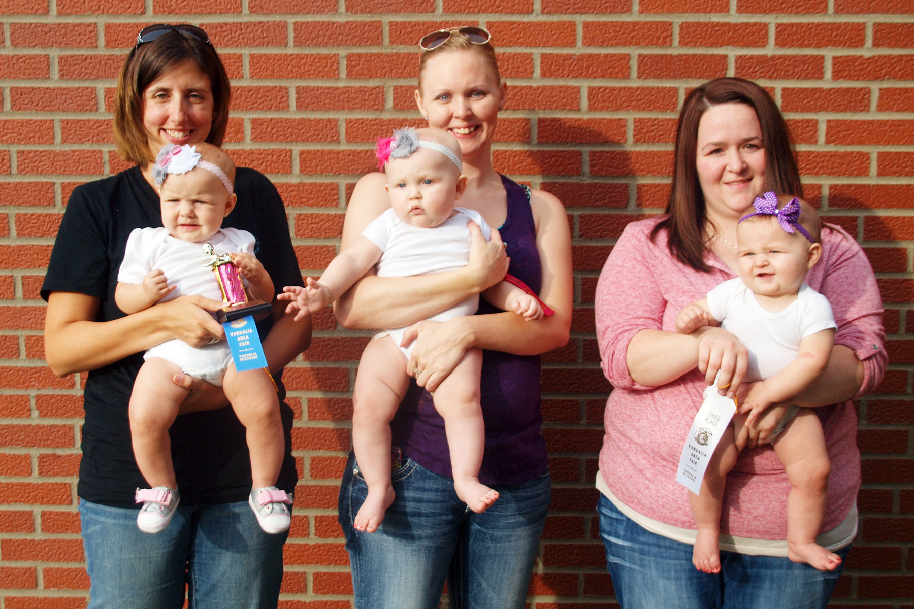 four women and one child are standing in front of a brick wall