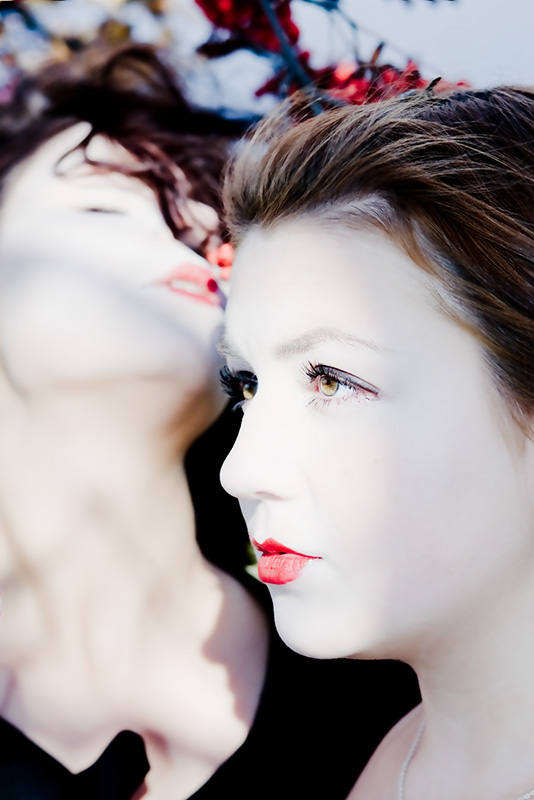 two woman wearing long black dress with red lipstick are looking off to the side