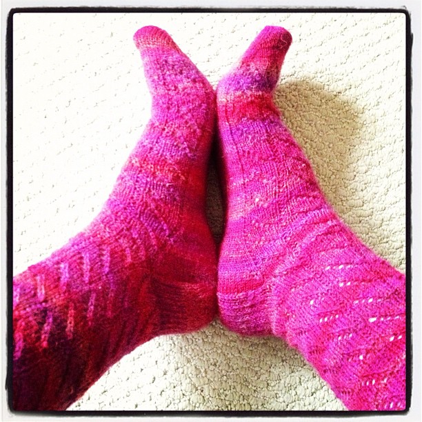 a pair of socks with pink knitted pattern sitting next to each other