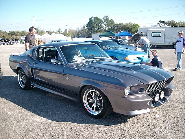 a gray and red ford mustang sitting in a parking lot