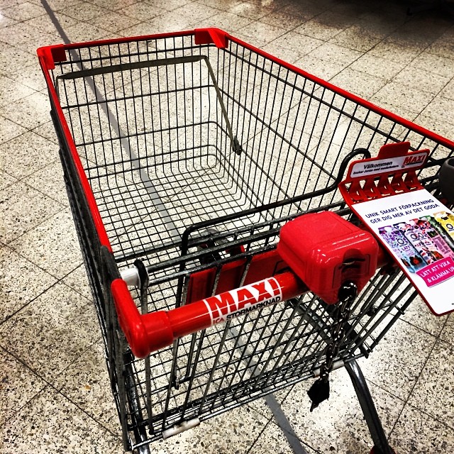 a red and black shopping cart sitting on the ground