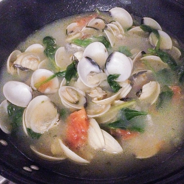 a bowl filled with clams and soup sitting on a stove