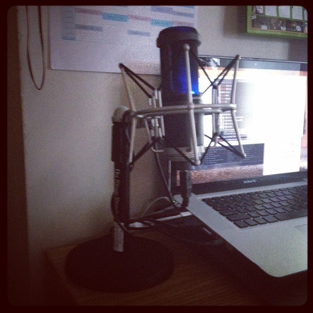 a microphone on top of a laptop computer next to a microphone stand